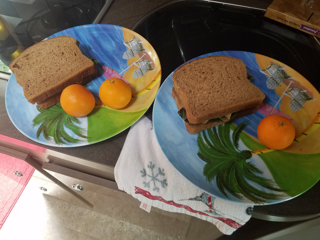Sandwiches and oranges on plates
