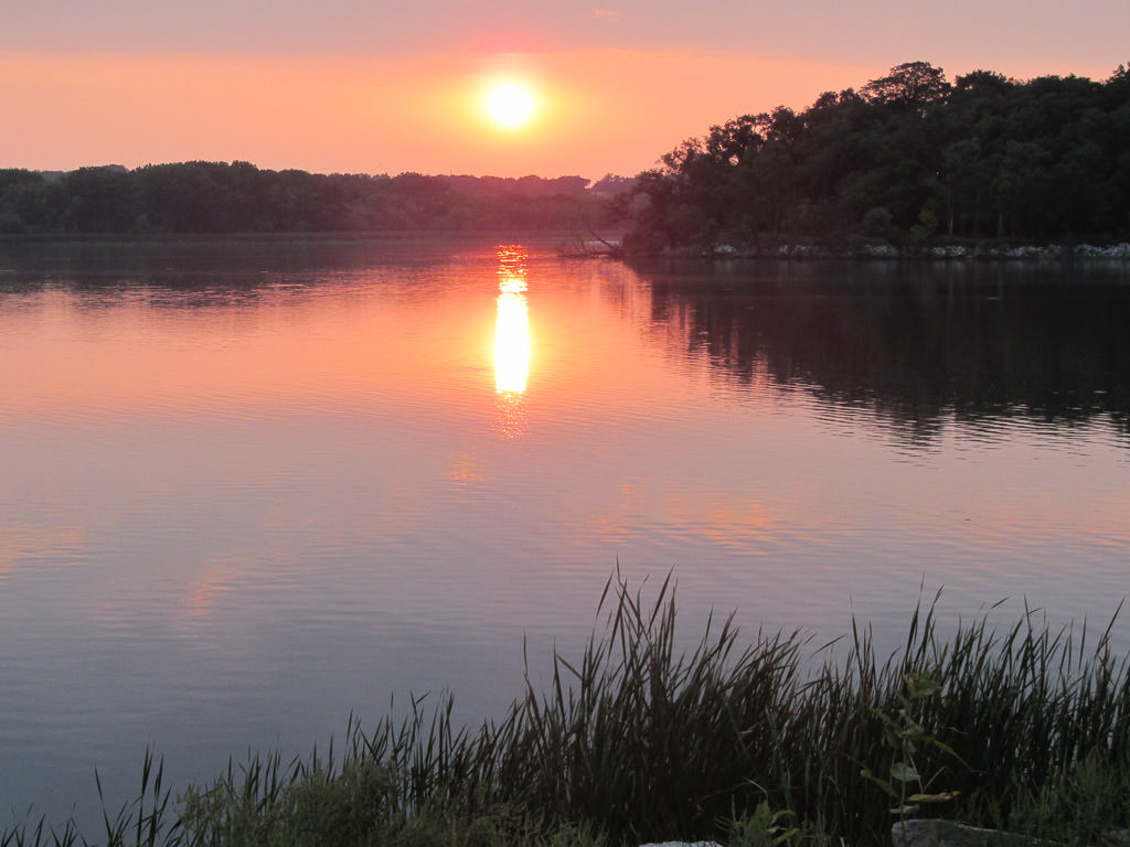 Beautiful sunset over the tree surrounded lake.